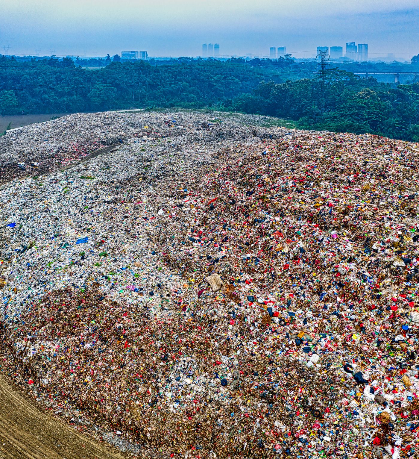 Aerial view of an overflowing landfill beside a city